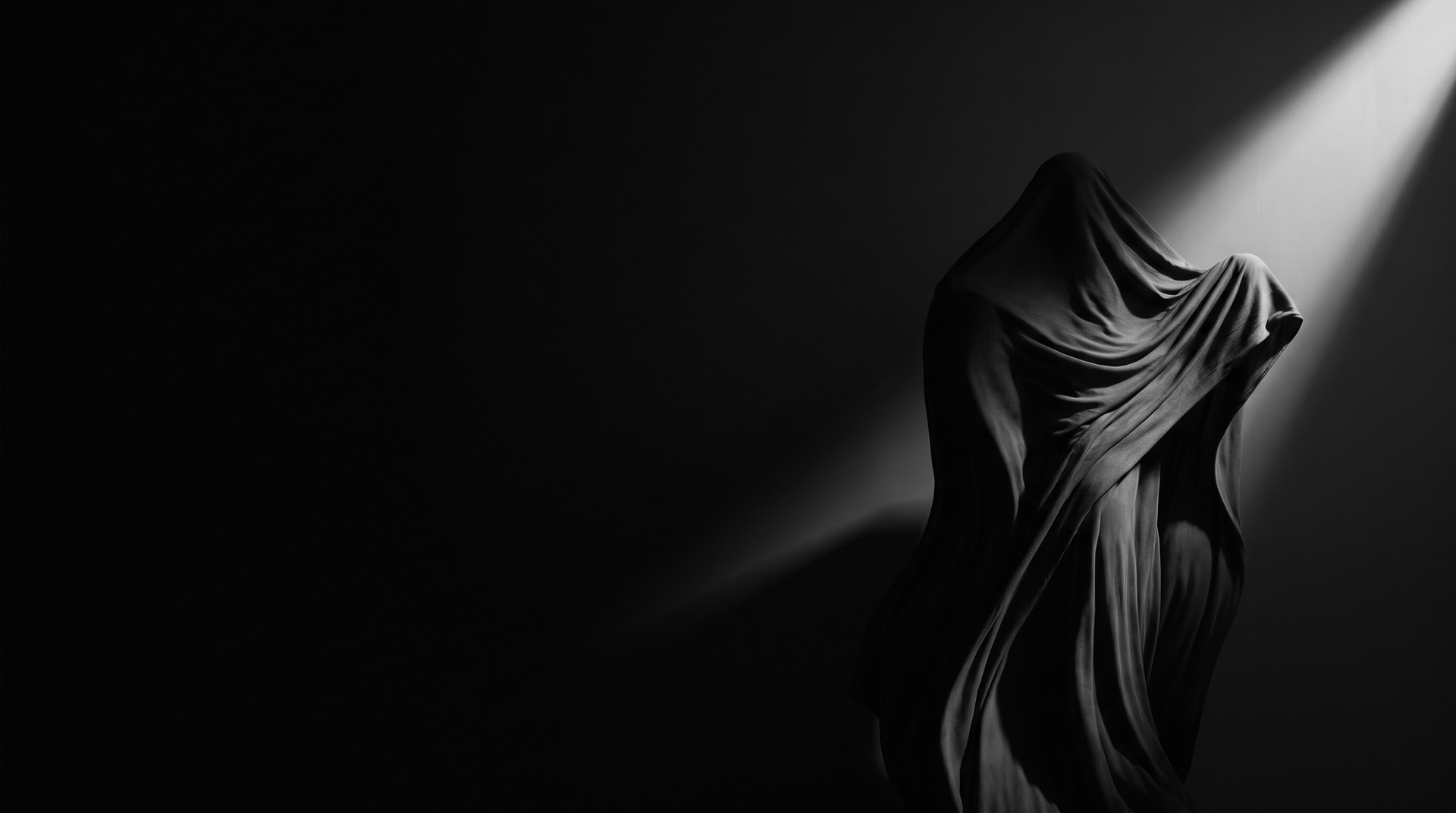 Sculpture drapée saisie dans un rai de lumière, photographie noir et blanc